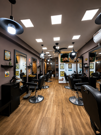 Interior da Barbearia Luma com cadeiras pretas de couro, espelhos e piso de madeira